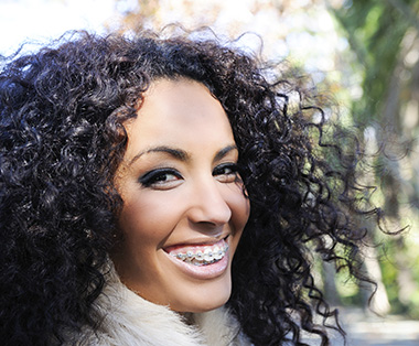 Beautiful woman with curly hair smiling wide to show off metal braces