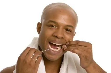 A man flosses his teeth to prevent gum disease damage in Loveland.