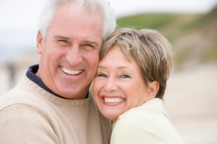 An elderly couple enjoying renewed smiles on the beach thanks to restorative dentistry in Montgomery.