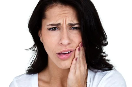 A woman clutching her jaw because of TMJ pain in Loveland.